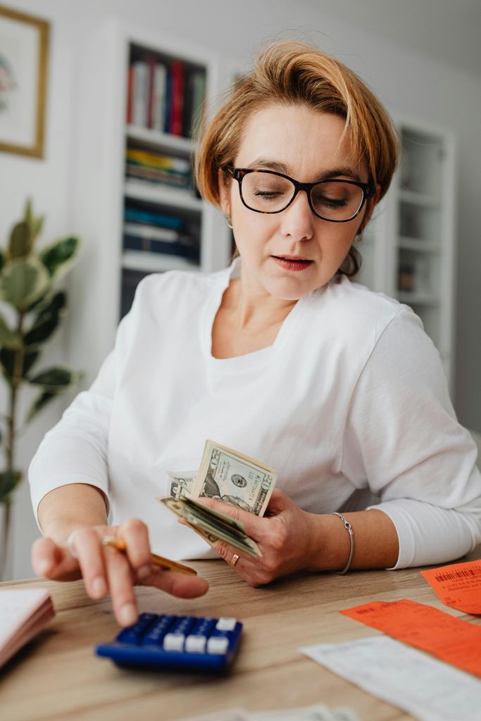 Woman Counting Money and Receipts on a Calculator 