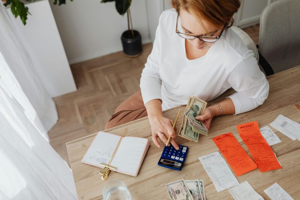 Woman Computing while Holding Dollar Bills